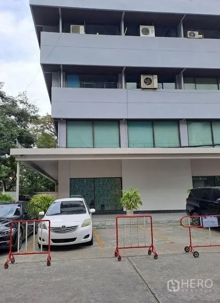 Office Space for rent in Khlong Toei, Bangkok - Low-rise office building exterior in Bangkok with parking bays and visible air-conditioning units.