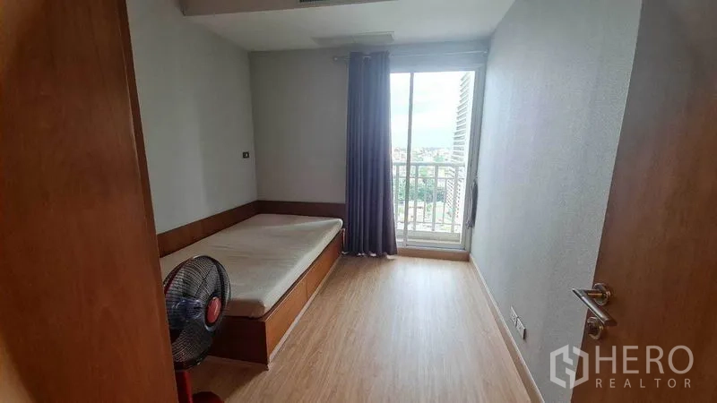 Condominium for rent or sale in Watthana, Bangkok - Second bedroom with single bed, wood flooring, and sliding doors to a small balcony.