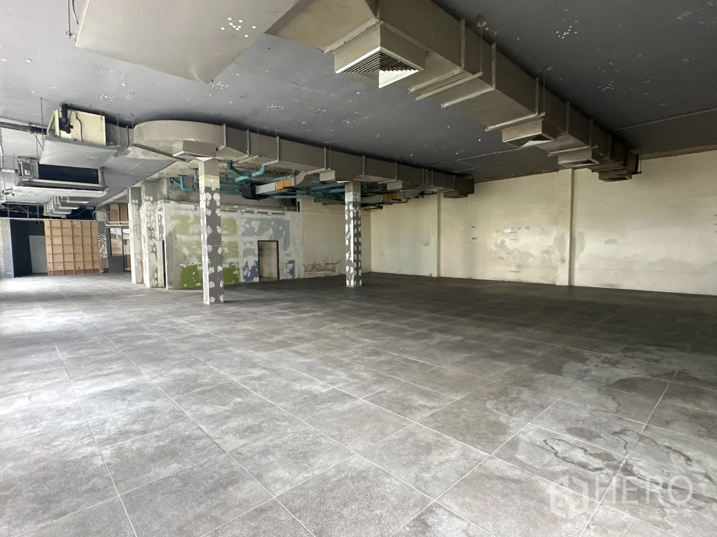 Retail Space for rent in Watthana, Bangkok - Wide tiled showroom space with structural columns and ventilation.