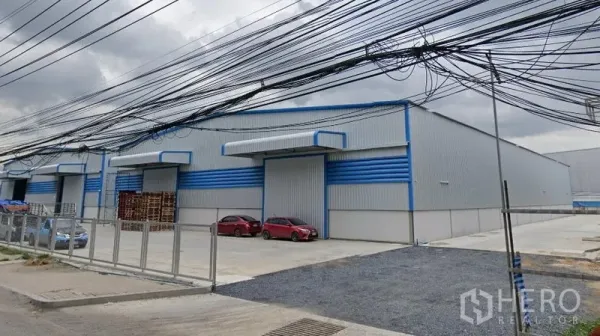 คลังสินค้า ให้เช่าในBang Phli, Samut Prakan - คอมเพล็กซ์โกดังติดถนน มีกำแพงรั้ว ลานจอดรถ และสายไฟเหนือศีรษะ