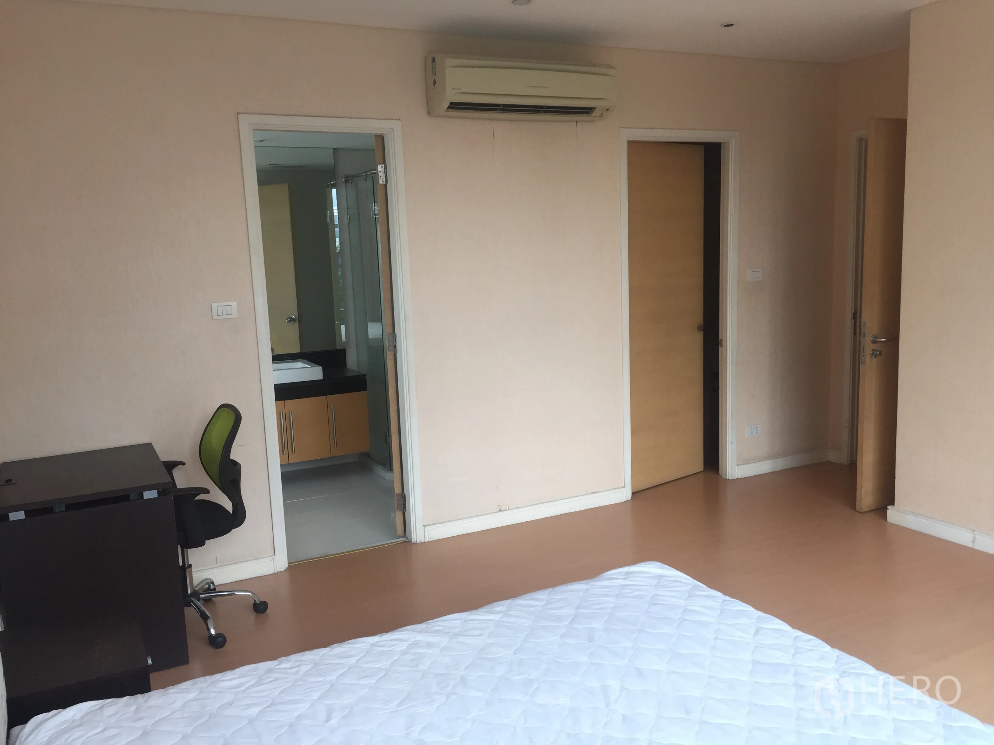 Condominium for rent or sale in Watthana, Bangkok - Spacious master bedroom with desk and doorway to an ensuite bathroom.