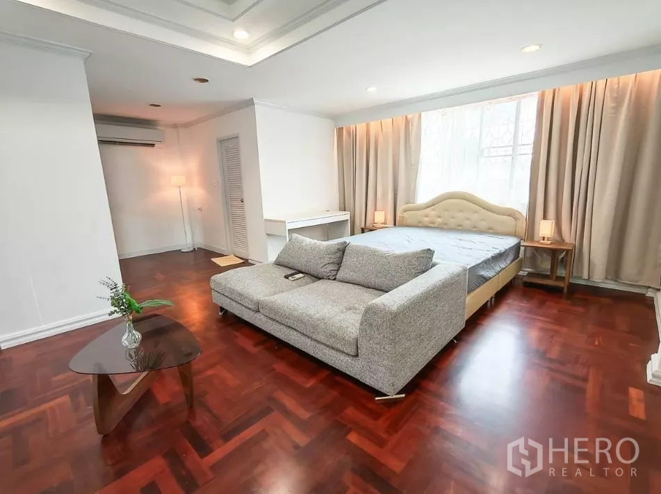 บ้าน ให้เช่าในYan Nawa, Bangkok - ห้องนอนพร้อมโซฟาสีเท้าท้ายเตียงและพื้นไม้ขัดเงา