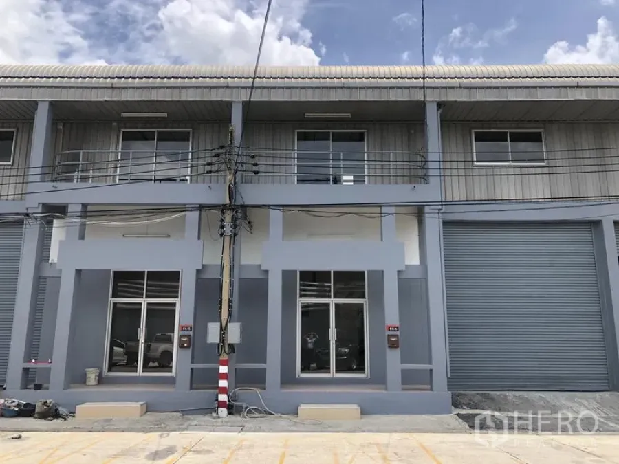 Factory for rent in Pak Kret, Nonthaburi - Modern two-storey factory frontage with glass doors and a roller shutter in a secure compound.