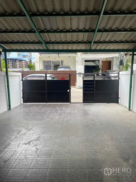 สำนักงานที่บ้าน ให้เช่าหรือขายในSuan Luang, Bangkok - ที่จอดรถมีหลังคา พื้นกระเบื้อง พร้อมประตูเหล็กสีดำเปิดสู่ถนน