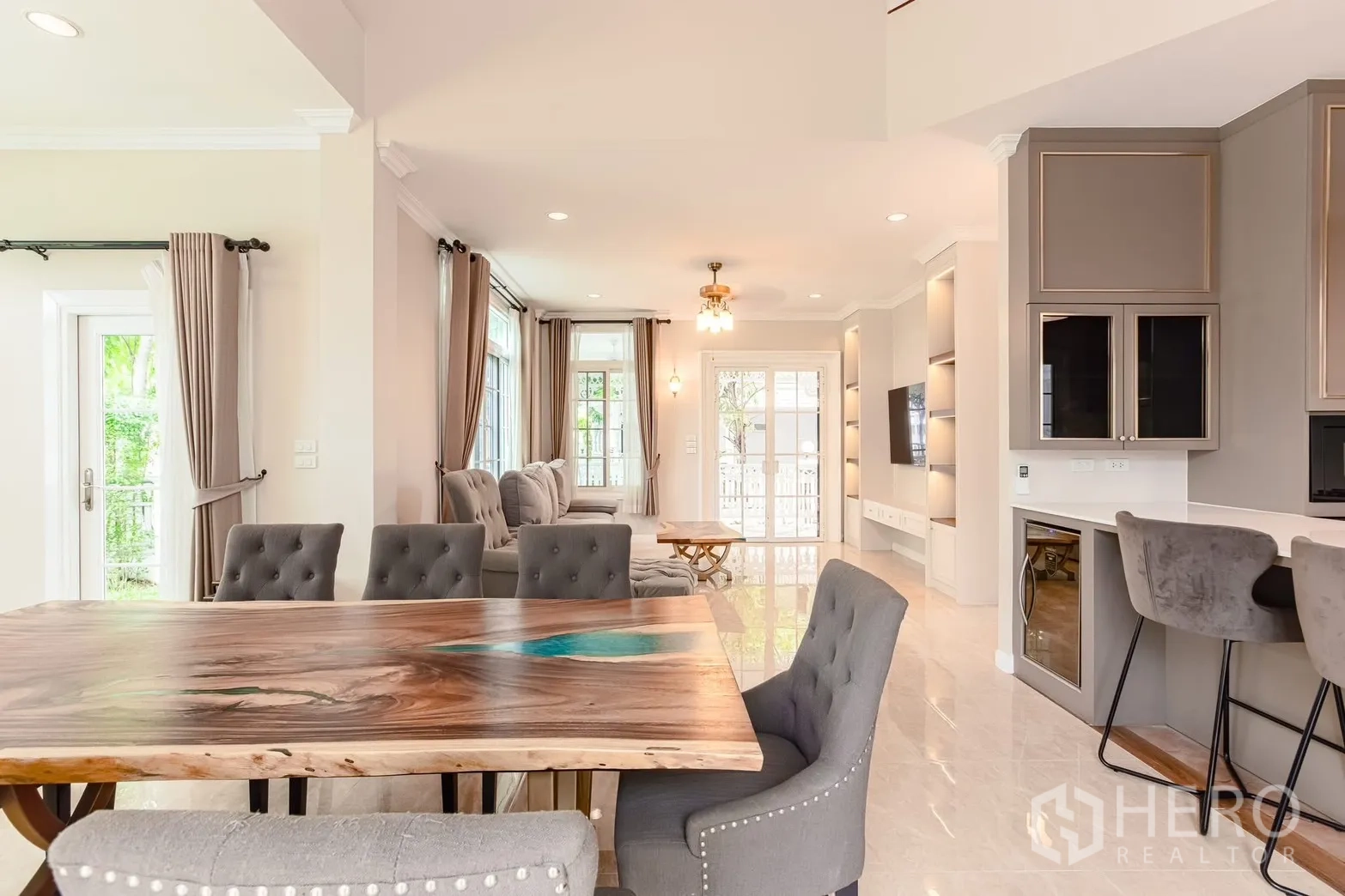 Detached House for rent in Bang Na, Bangkok - Open-plan living and dining area with tufted chairs, glossy floor, and built-in TV wall.