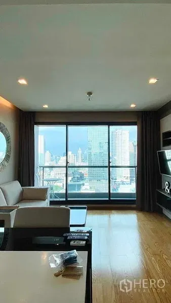 Condominium for rent or sale in Bang Rak, Bangkok - Living room facing a balcony with sliding glass doors and panoramic city views.