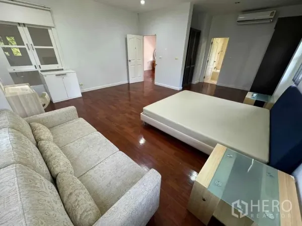 Detached House for rent in Prawet, Bangkok - Large master bedroom with sofa seating, wooden floors and access to an ensuite.