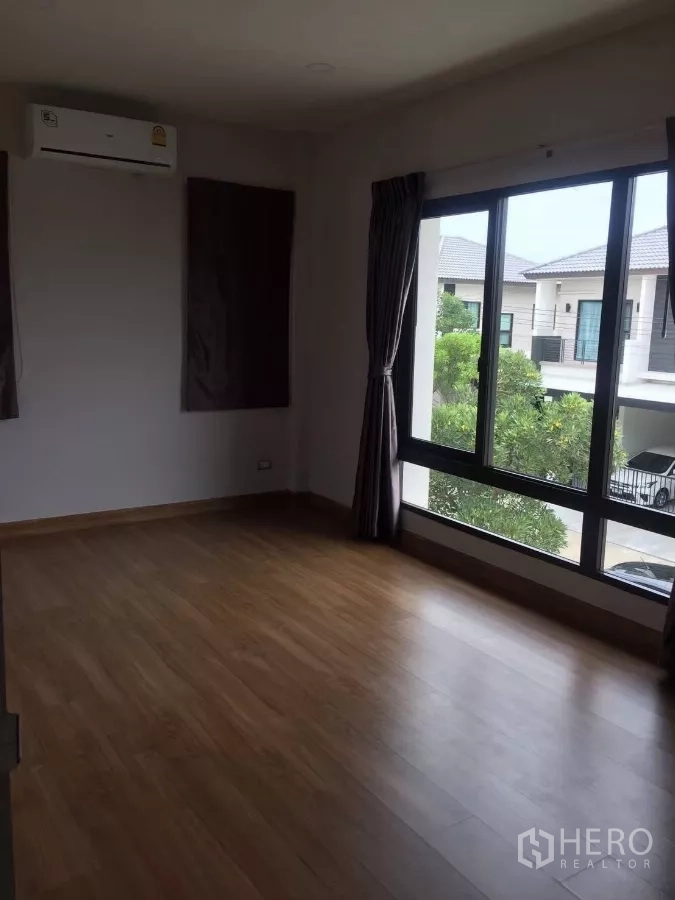 Detached House for rent in Samut Prakan - Spacious upstairs bedroom with large corner windows, wood floors and an air conditioner.