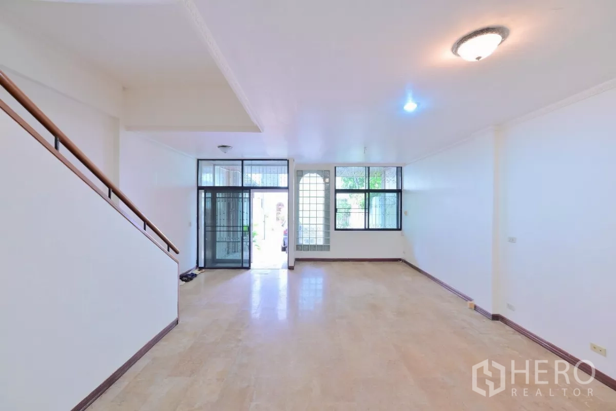 Townhouse for sale in Watthana, Bangkok - Front living space viewed from the stairs, featuring glass-block window and sliding entrance doors.