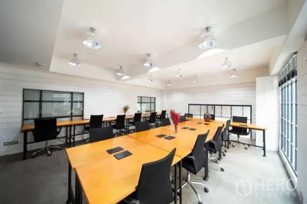 สำนักงาน ให้เช่า - สำนักงานแผนผังเปิด โล่งสว่าง โต๊ะไม้ยาว เก้าอี้สีดำ ผนังสีขาว และหน้าต่างบานใหญ่ ในย่านทองหล่อ