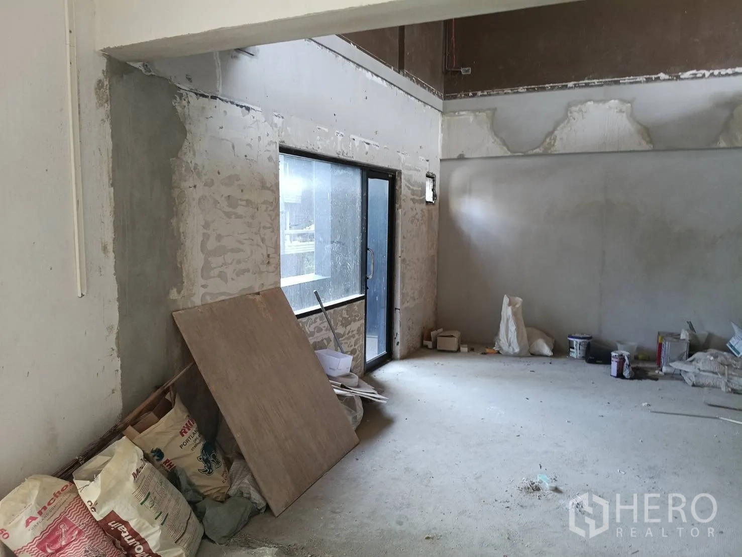 Retail Space for rent - Raw open‑plan space with sliding glass door and renovation materials.