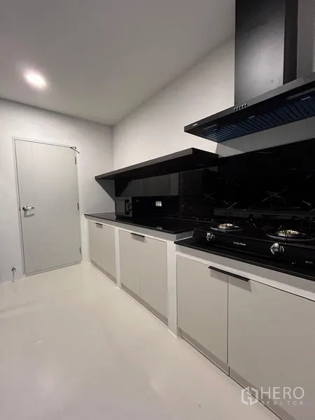 Detached House for rent or sale in Bang Phli, Samut Prakan - Second angle of the Thai kitchen showing range hood and glossy black backsplash.