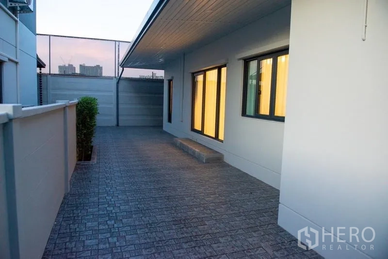 Detached House for rent in Bang Phli, Samut Prakan - Paved side yard walkway with windows and privacy wall.