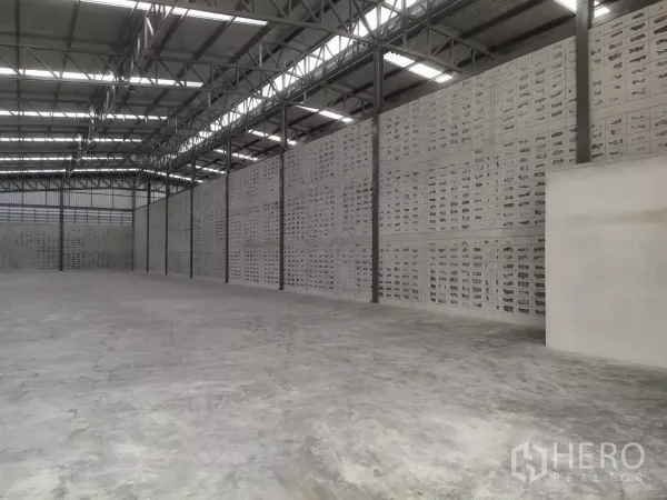 Warehouse for rent in Samut Prakan - Side view of the warehouse showing ventilated block walls, steel columns and smooth concrete flooring.