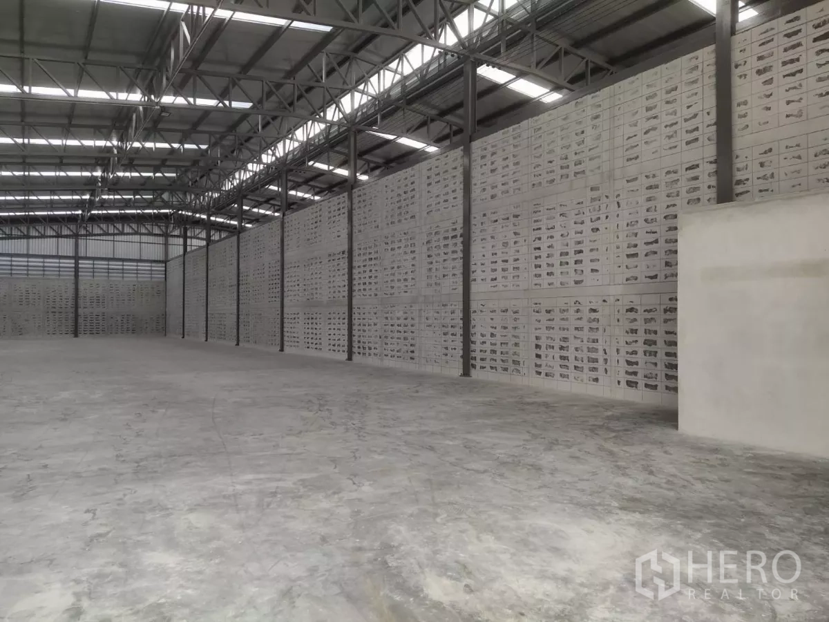 Warehouse for rent in Samut Prakan - Side view of the warehouse showing ventilated block walls, steel columns and smooth concrete flooring.