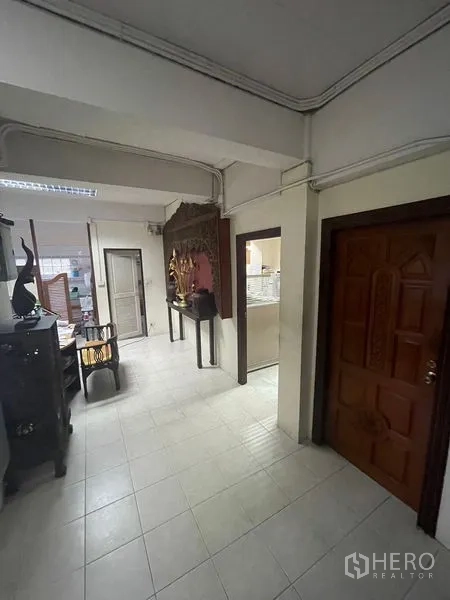 Home Office for sale in Yan Nawa, Bangkok - Hallway with tiled flooring, a wooden door, and a decorative niche.