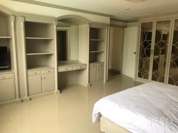 Condominium for rent in Watthana, Bangkok - Spacious primary bedroom featuring built‑in wardrobes, open shelving and a dressing desk.