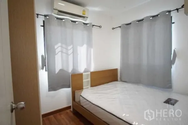 ทาวน์เฮาส์ ให้เช่าในSuan Luang, Bangkok - ห้องนอนขนาดกะทัดรัด เตียงและแอร์ ผ้าม่านสีเทา พื้นไม้