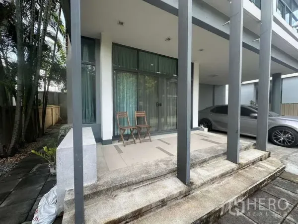 Detached House for rent or sale in Bang Kapi, Bangkok - Front terrace with tall columns, sliding glass doors and seating beside the covered carport.