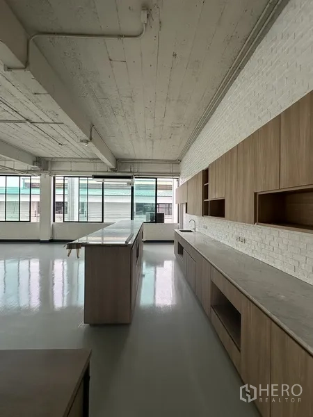 Office Space for rent - Pantry area with long stone countertops, wood cabinets and wide windows.