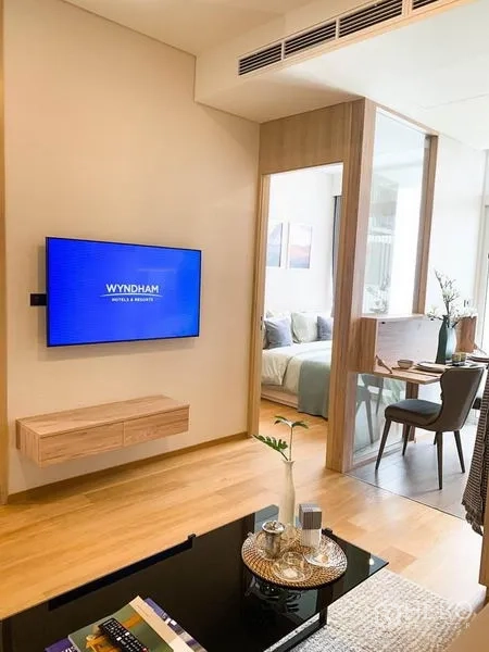 คอนโด ขายในKhlong Toei, Bangkok - ห้องนั่งเล่นทีวีติดผนัง พื้นไม้ และฉากกั้นกระจกบานเลื่อนเชื่อมห้องนอนกับมุมทานอาหาร