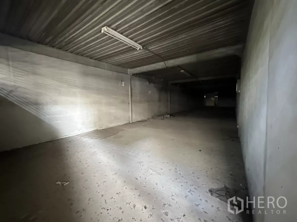 Warehouse for rent in Suan Luang, Bangkok - Low-ceiling storage room with concrete floor and fluorescent lighting inside the warehouse.