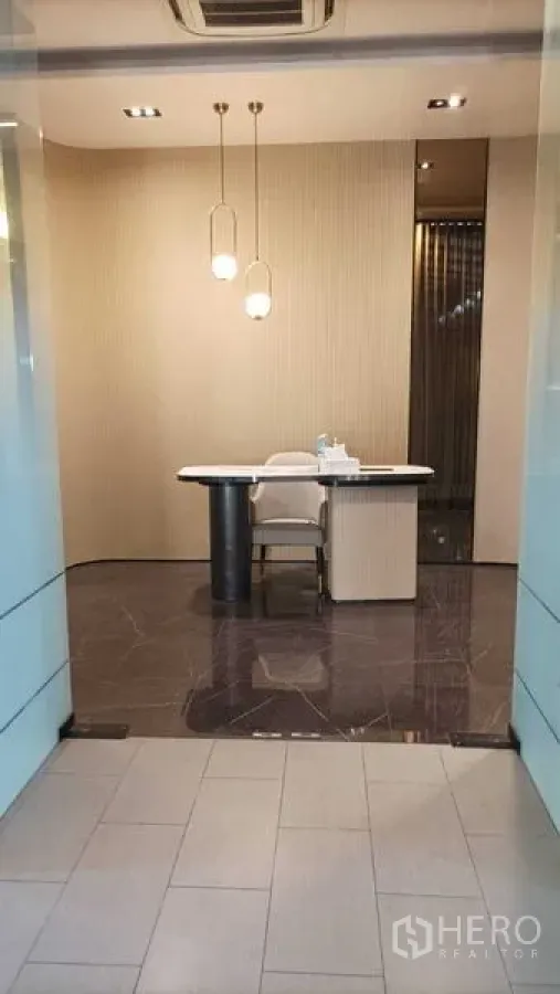 零售空间 出租 - 现代零售前台，石纹地面、吊灯与时尚办公桌，从玻璃门望入。