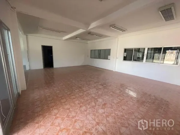 Factory for rent in Sam Khok, Pathum Thani - Open-plan admin space with terracotta tiles, ceiling lights and sliding glass door.