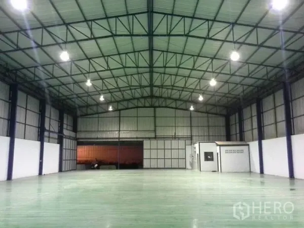 货栈 出租在Chon Buri - 开阔仓库内景，角落带小型办公室，卷帘门与环氧地坪