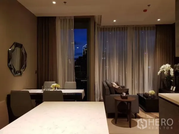 Condominium for rent in Watthana, Bangkok - Open-plan dining and living area at night with sheer drapes and recessed lighting.