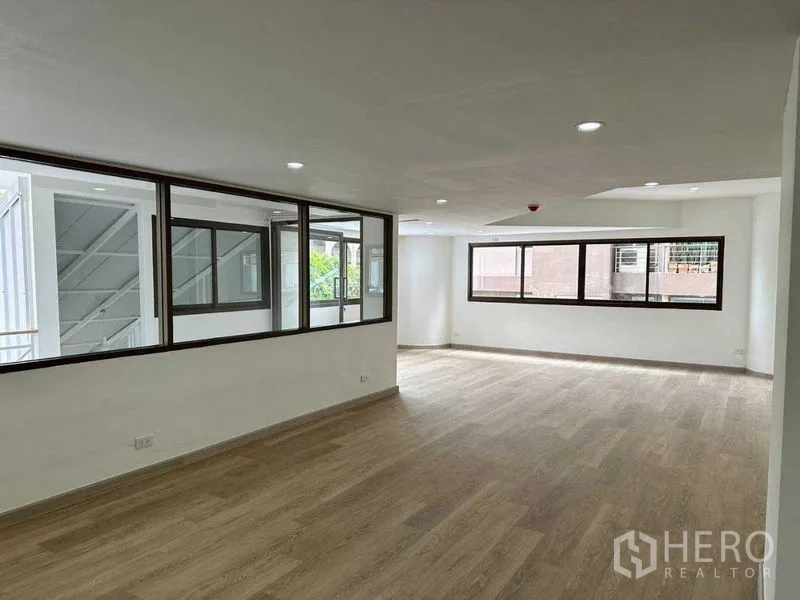 Office Space for rent or sale in Khlong Toei, Bangkok - Upper mezzanine office room with wood-look flooring and wide windows.
