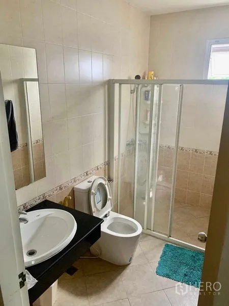 独立式住宅 出租在Prawet, Bangkok - 瓷砖浴室，滑动玻璃淋浴间、坐便器与单盆台面。