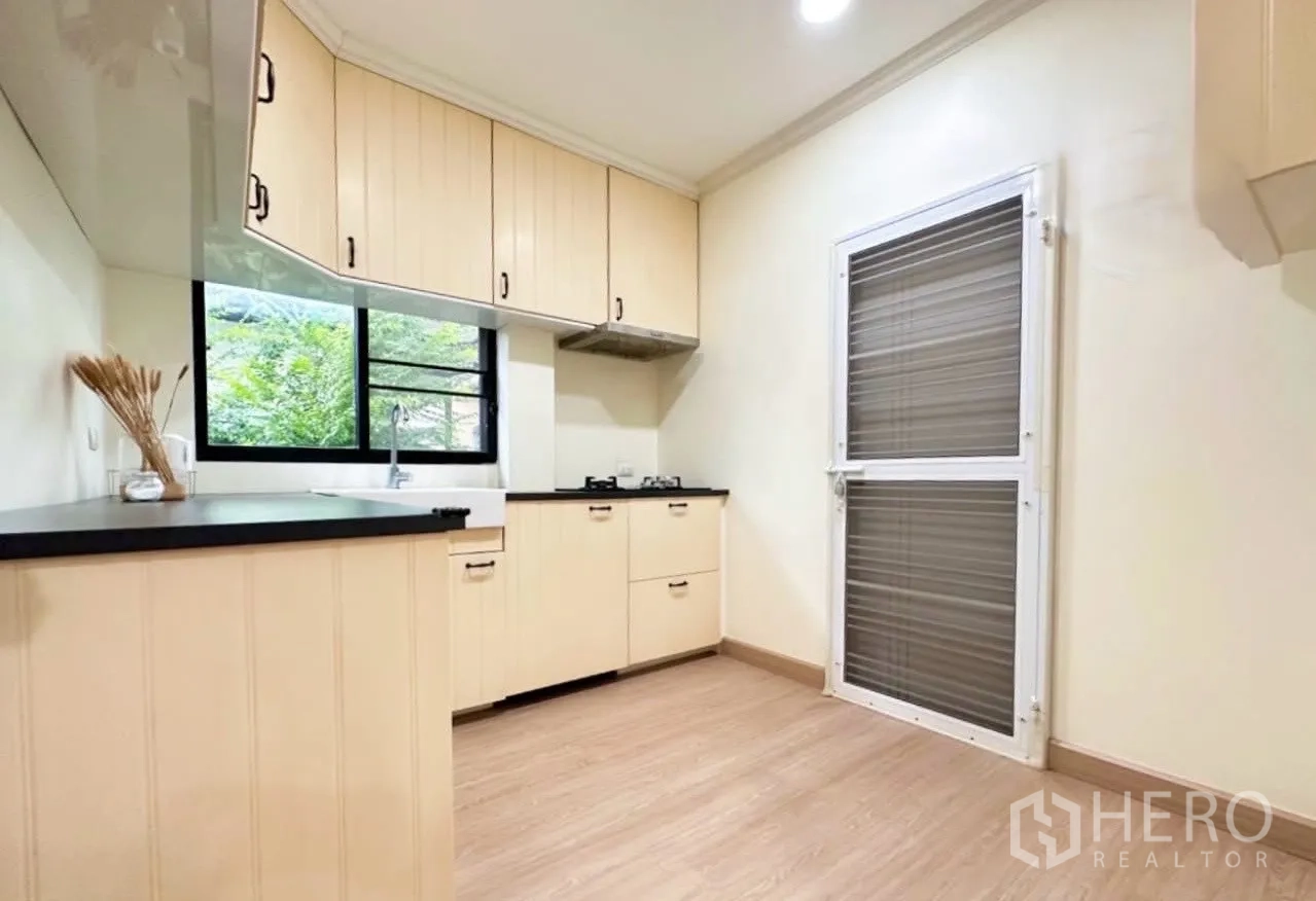 บ้าน ขายในLam Luk Ka, Pathum Thani - ห้องครัวมีประตูหลังบ้าน ตู้แขวน ซิงก์ริมหน้าต่าง และพื้นที่ใช้งานกว้าง