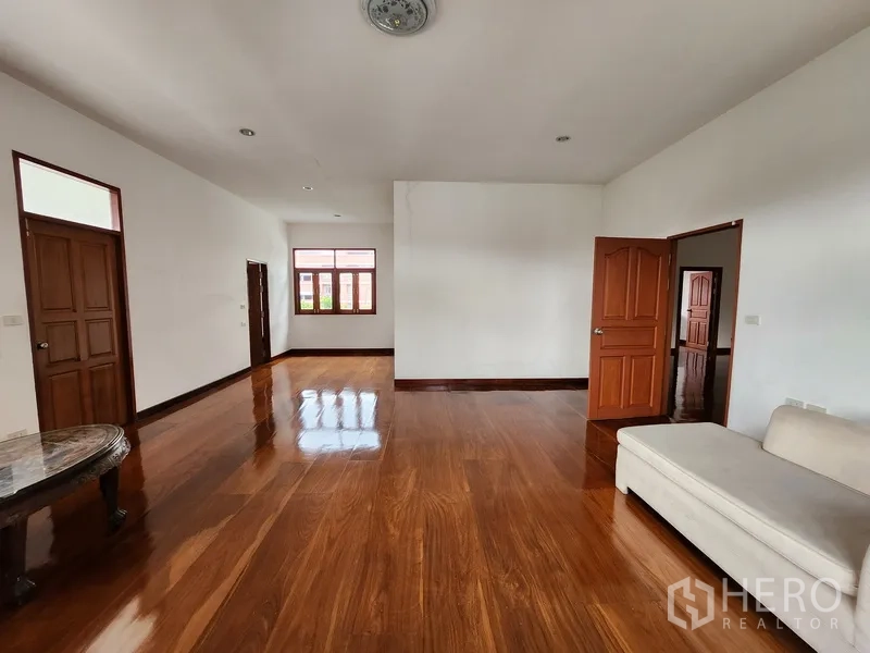 独立式住宅 出租在Prawet, Bangkok - 二层起居区，设沙发与木地板，大窗采光良好。