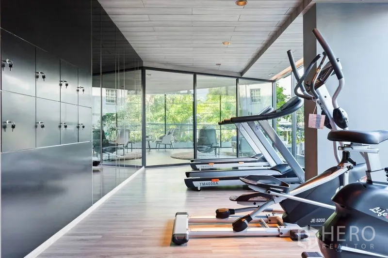Condominium for rent or sale in Watthana, Bangkok - Condo fitness center with treadmills facing garden views and secure lockers.