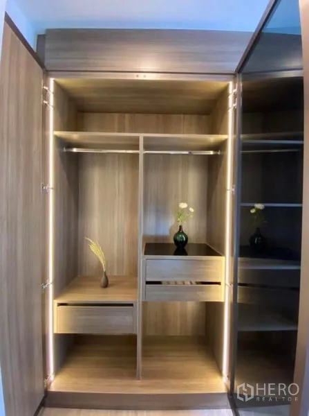 公寓 出租或出售在Phaya Thai, Bangkok - 打开的木质衣柜，带照明、抽屉与挂衣区。