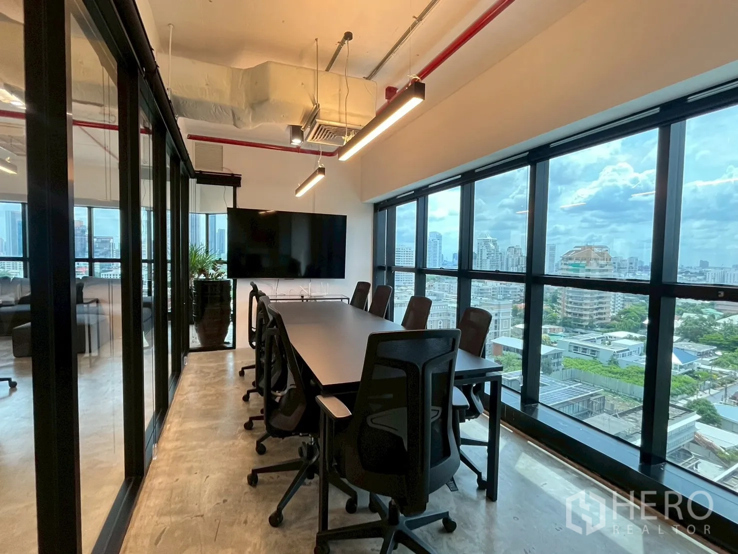 办公室 for rent in Watthana, Bangkok - 玻璃围合的会议室，配置长桌、椅子与大屏幕，窗外为城市景色。