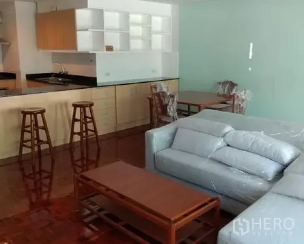 อพาร์ทเมนท์ ให้เช่าในPathum Wan, Bangkok - พื้นที่นั่งเล่นและครัวแบบเปิดโล่ง พร้อมเคาน์เตอร์บาร์ เก้าอี้สูง ชุดโต๊ะอาหาร และโซฟา ในอพาร์ตเมนต์เขตปทุมวัน