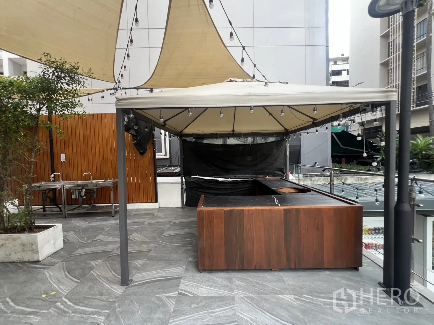 พื้นที่ขายปลีก ให้เช่า - คีออสบาร์กลางแจ้งใต้กันสาดผ้าใบ พร้อมไฟสายประดับ บนพื้นกระเบื้องลานกว้าง