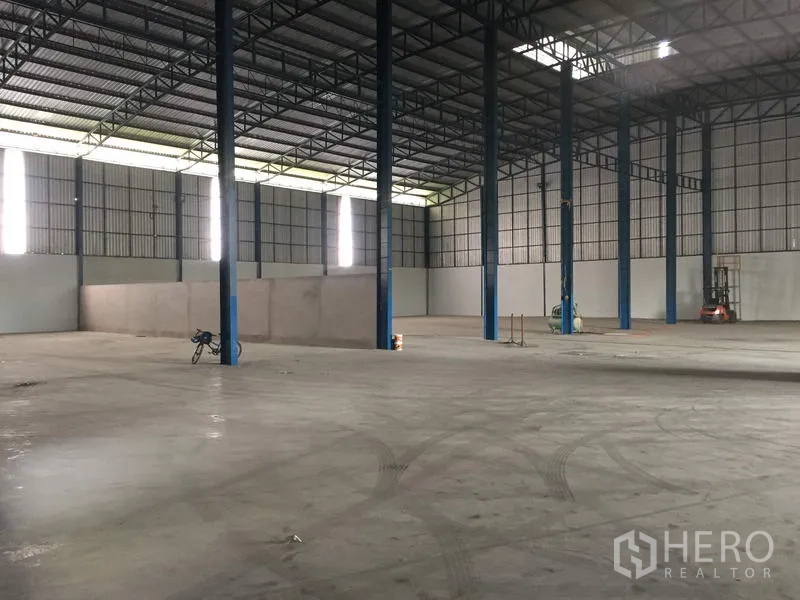 Warehouse for rent in Pathum Thani - Open-plan storage hall with steel columns, skylight panels, and wide maneuvering space.