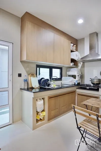 独立式住宅 出租或出售在Bang Kapi, Bangkok - 紧凑泰式厨房，燃气灶与不锈钢烟机，石质台面和浅木色橱柜。