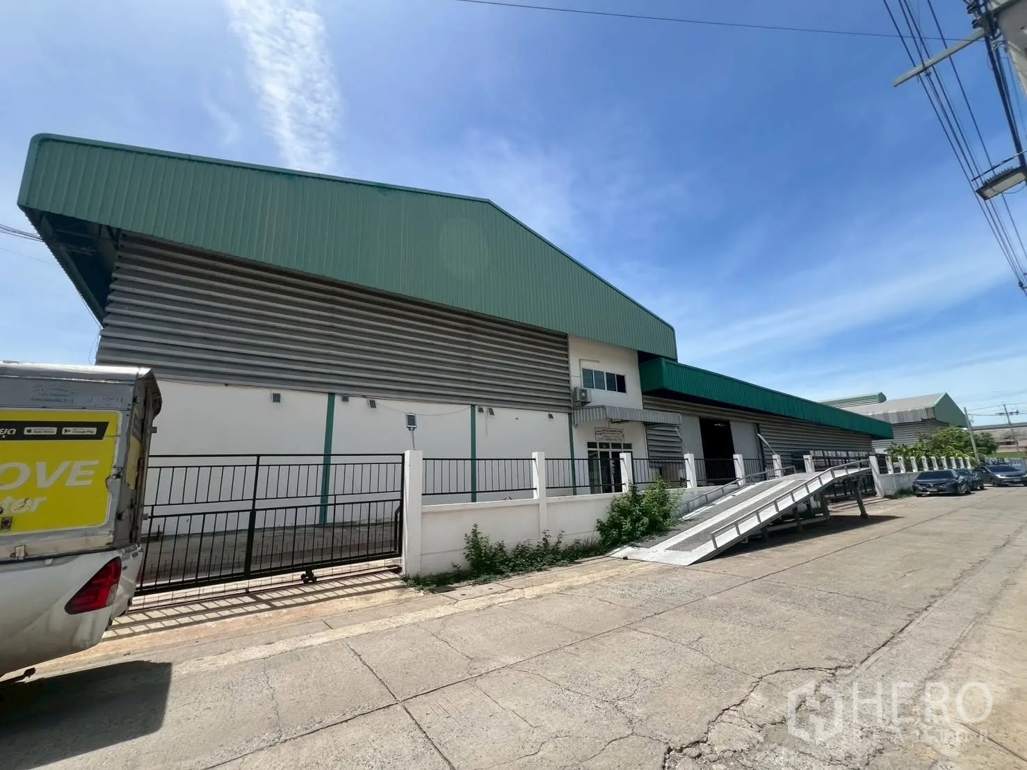 Warehouse for rent in Bang Phli, Samut Prakan - Warehouse exterior with loading ramp, multiple roller shutter bays, fence, and on-site parking.