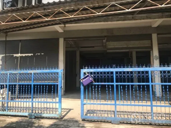 货栈 出租在Bueng Kum, Bangkok - 仓库外立面，蓝色金属围栏与卷闸门，遮棚下的装卸区。