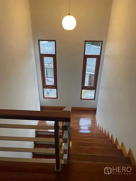 Detached House for sale in Bang Khun Thian, Bangkok - Polished wooden staircase with tall vertical windows and a pendant light.