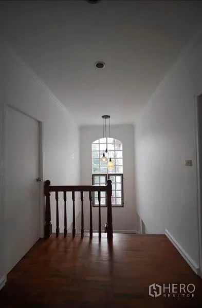 独立式住宅 出租在Bang Phli, Samut Prakan - 二层走廊，拱形窗、吊灯与木扶手。