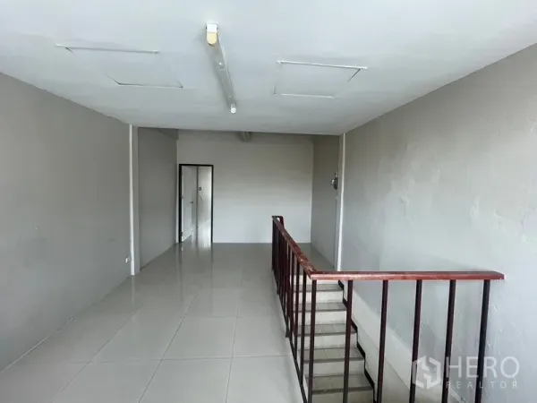 店屋 出租在Phra Khanong, Bangkok - 楼上一层开放空间，亮面地砖与楼梯护栏。