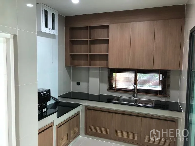 Detached House for rent in Bang Kapi, Bangkok - Modern Western kitchen featuring wood cabinetry, black stone counters and a window.