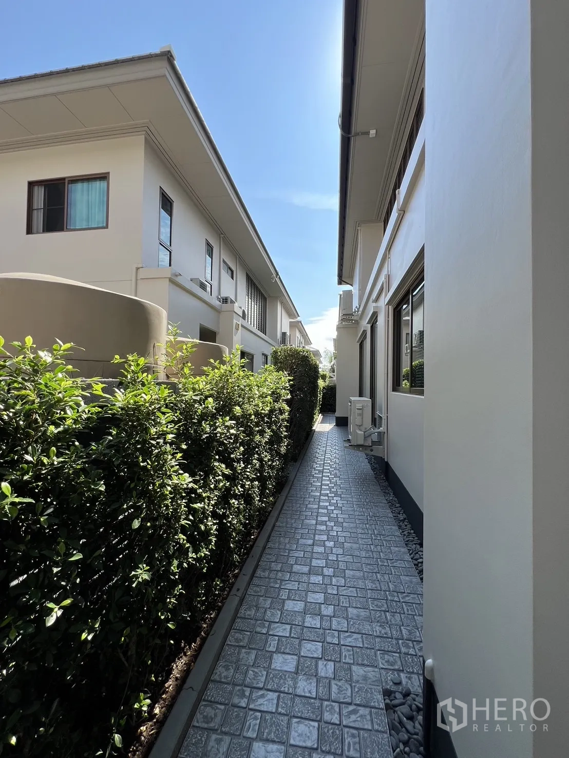 Detached House for rent or sale in Bang Kapi, Bangkok - Service walkway with textured paving and clipped hedges between houses.