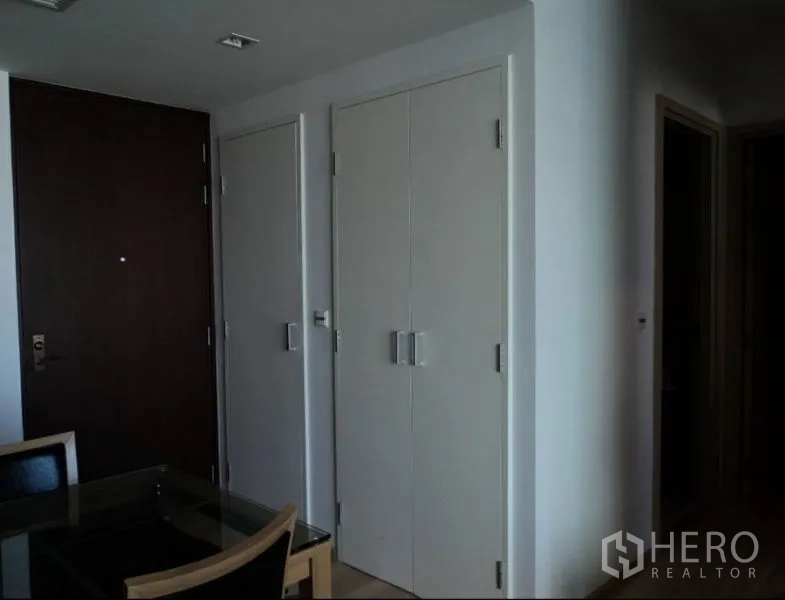 คอนโด ให้เช่าในKhlong Toei, Bangkok - โถงทางเข้ามีประตูหลักสีไม้ ตู้เก็บของสีขาว และมุมรับประทานอาหาร