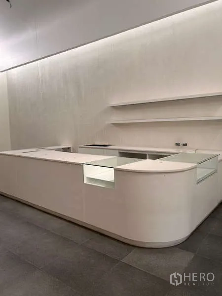 独立商业地产 出租在Khlong Toei, Bangkok - 白色U形销售或接待柜台，带搁架和隐藏灯带。